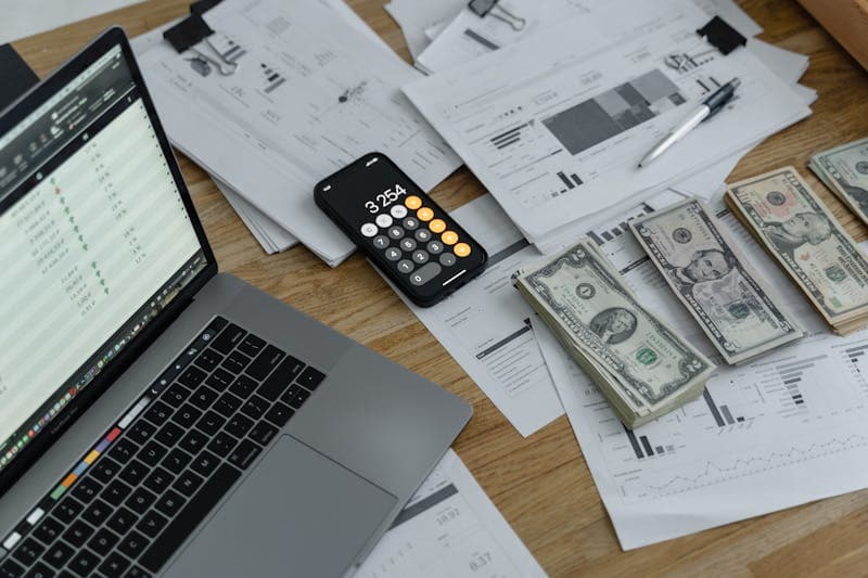 Freelance calculant ses charges et revenus avec une calculatrice et des documents financiers